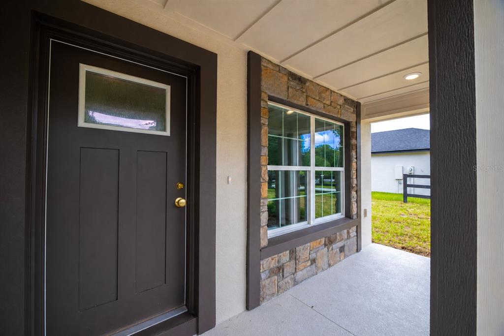 A covered front porch features a dark door, stone siding, and a large window — 4570 WINDEE AVENUE, LAKELAND, FL