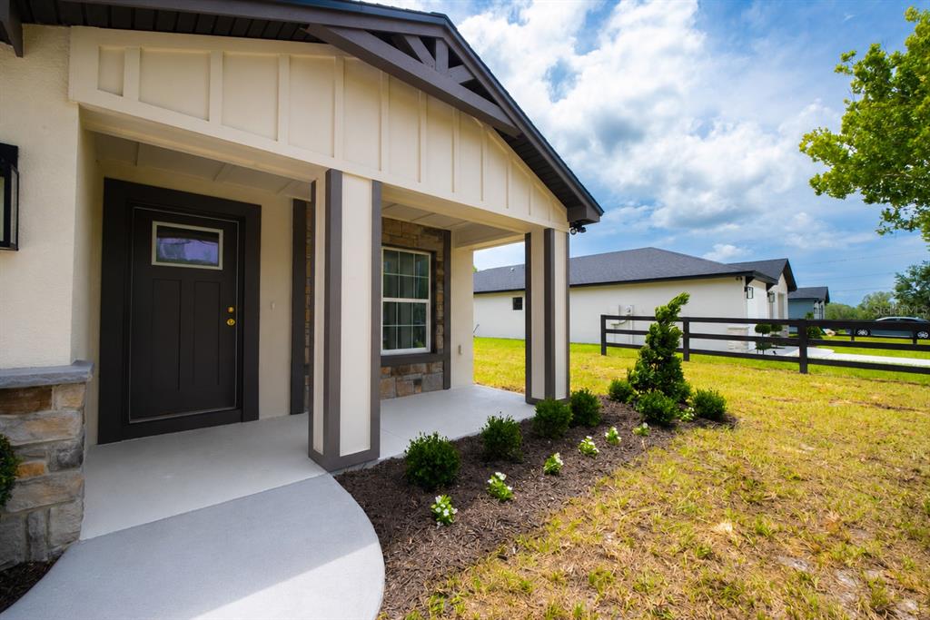 The exterior of a house features a covered porch, a dark front door, and landscaping — 4570 WINDEE AVENUE, LAKELAND, FL