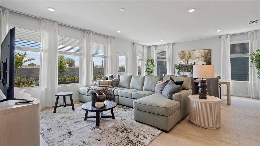 A living room features a large sectional sofa, a round coffee table, and floor-to-ceiling windows — 1880 FIELDSTONE STREET, MINNEOLA, FL