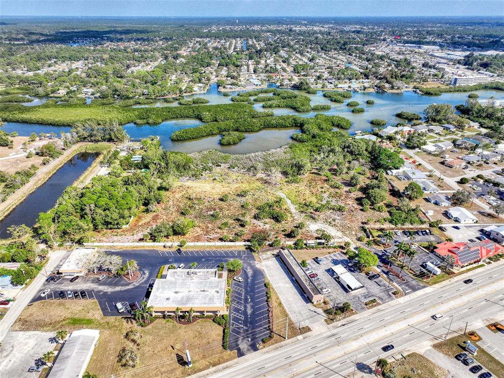 Aerial view of a commercial building with a parking lot adjacent to a coastal wetland — 201 E BAY HEIGHTS ROAD, ENGLEWOOD, FL