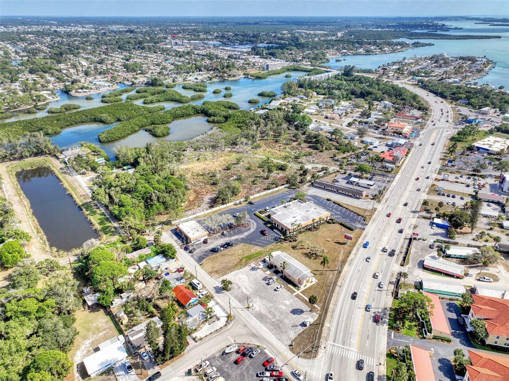 An aerial view shows a commercial property with parking lots situated near a coastal waterway — 201 E BAY HEIGHTS ROAD, ENGLEWOOD, FL