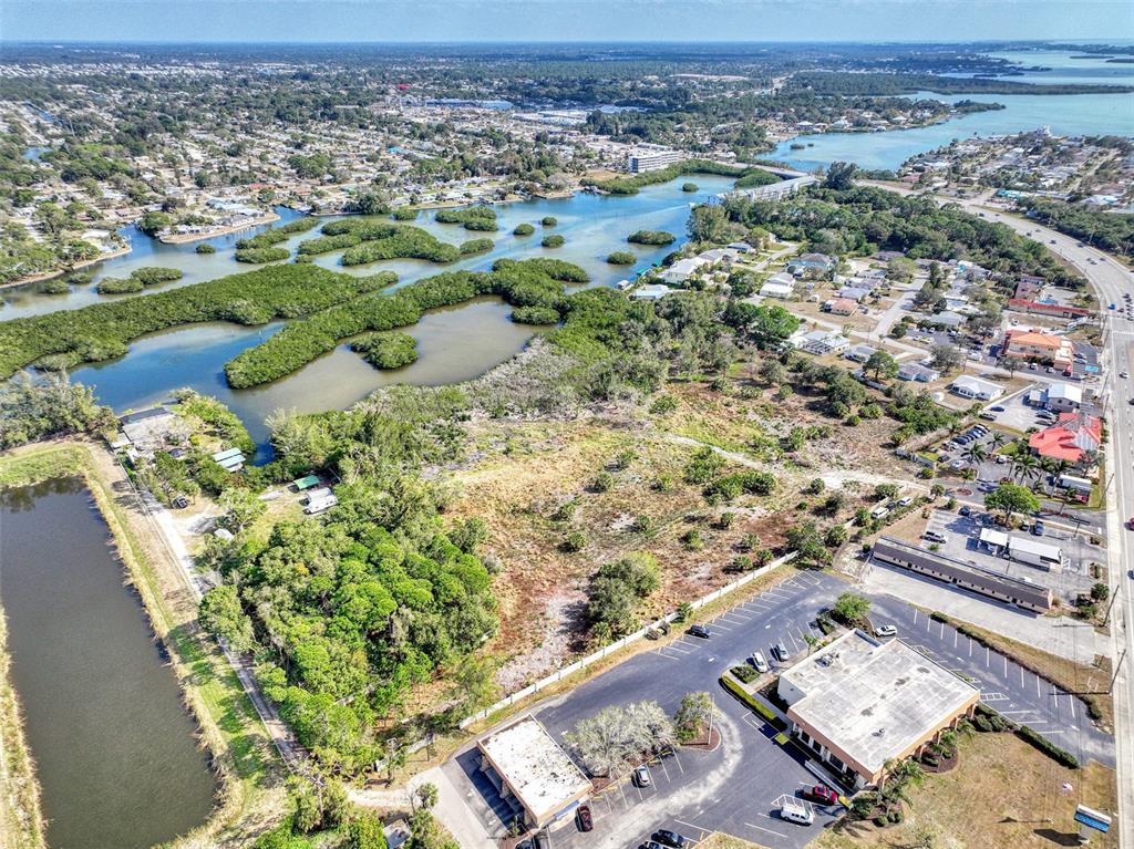 An aerial view shows a commercial building with a parking lot next to undeveloped land — 201 E BAY HEIGHTS ROAD, ENGLEWOOD, FL