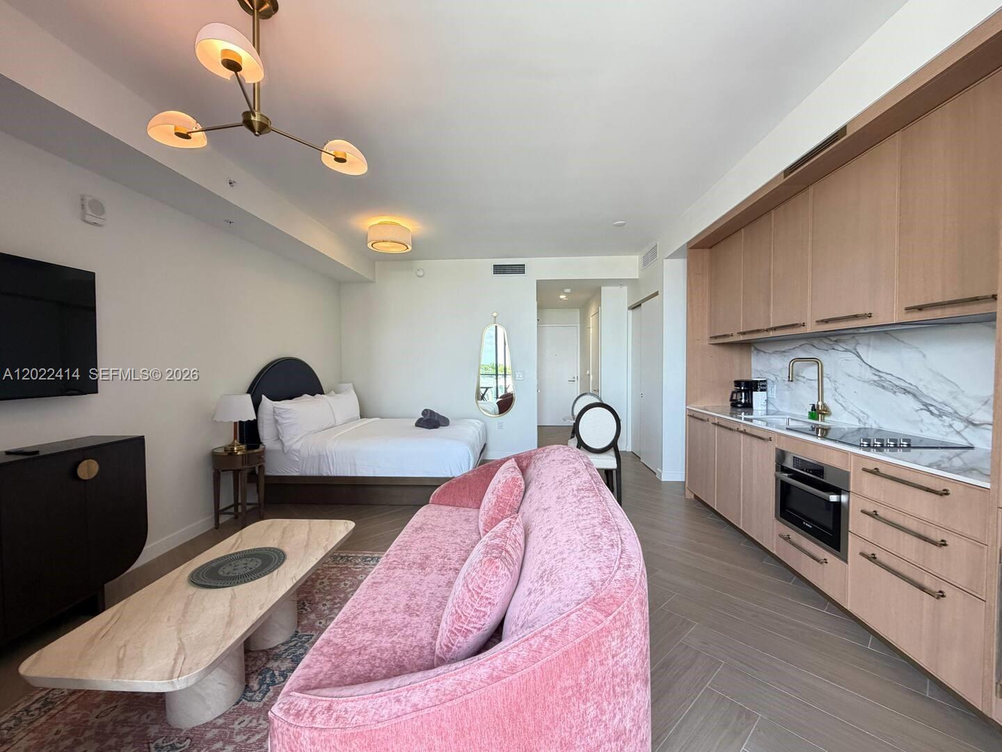 A studio apartment features a pink velvet sofa, a bed, and a modern kitchenette — 2700 NW 2nd Ave # 424, Miami FL 33127, MIAMI, FL