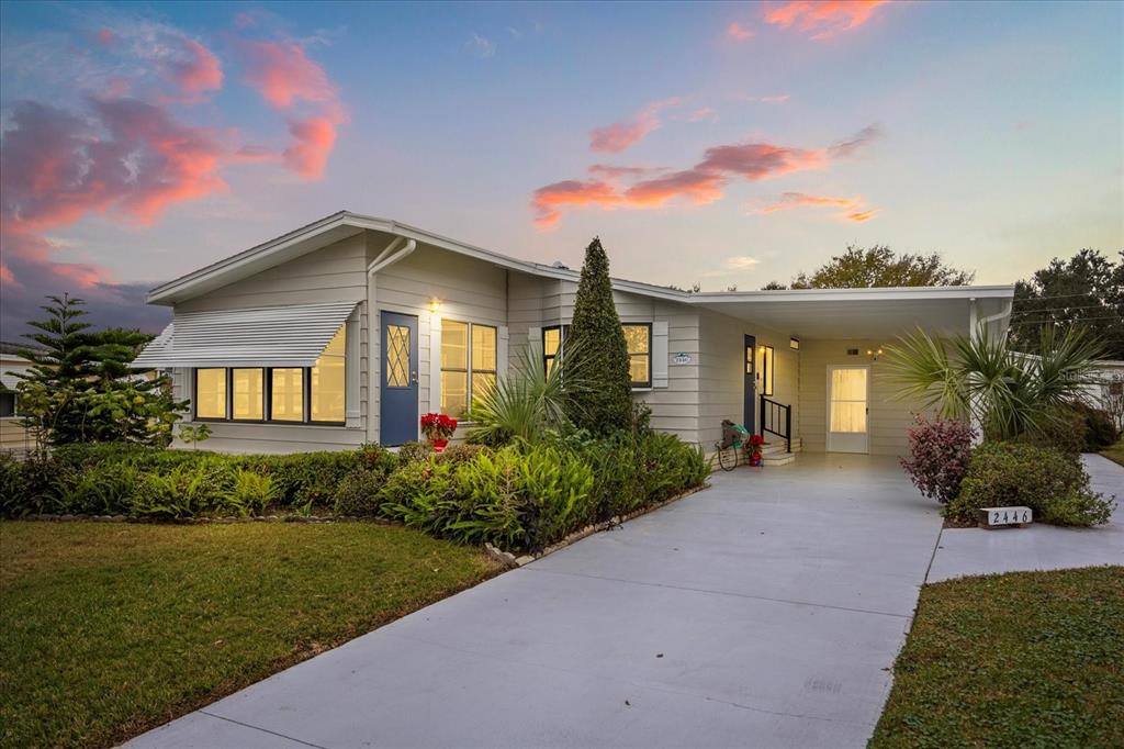 A single-story house with light gray siding, a carport, and a landscaped front yard — 2446 FAIRBLUFF CIRCLE UNIT 1554, ZELLWOOD, FL