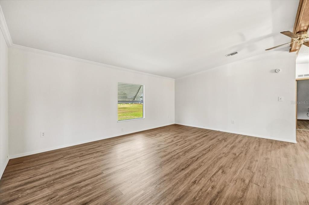 An empty room features white walls, wood-look flooring, a single window, and a ceiling fan — 2446 FAIRBLUFF CIRCLE UNIT 1554, ZELLWOOD, FL