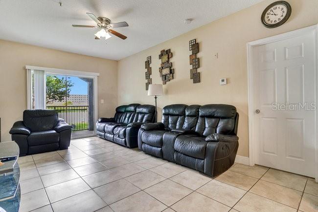 A living room features black leather furniture, tile flooring, and a sliding glass door — 3702 PALM DESERT LANE UNIT 5414, ORLANDO, FL