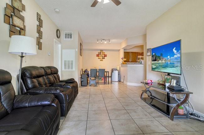 A living room features a black leather sofa, a floor lamp, and a television stand — 3702 PALM DESERT LANE UNIT 5414, ORLANDO, FL