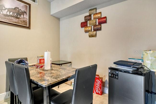A dining area features a marble-topped table, four black chairs, and wall-mounted metal art — 3702 PALM DESERT LANE UNIT 5414, ORLANDO, FL