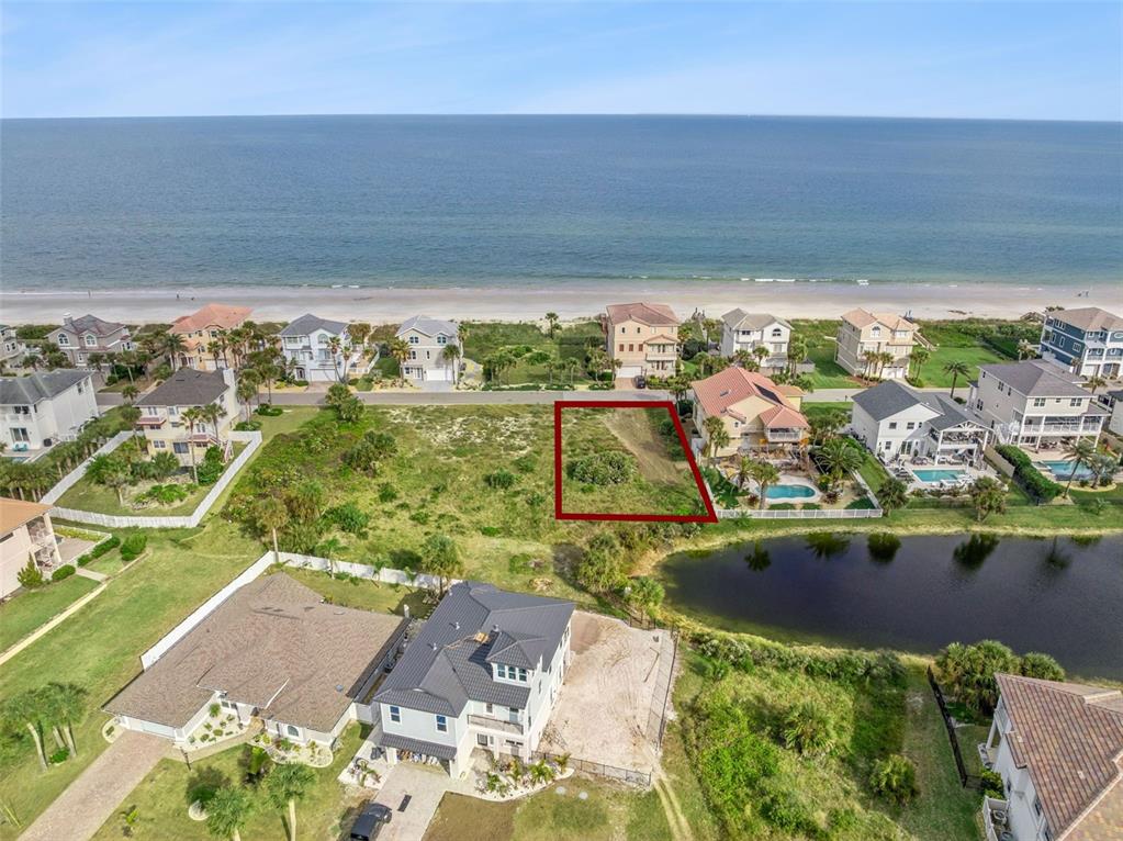 An aerial view shows a vacant, rectangular lot outlined in red near a coastal beach — 22 OCEAN DUNE CIRCLE, PALM COAST, FL