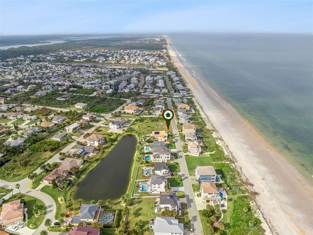 An aerial view shows a coastal neighborhood with houses situated between a pond and beach — 22 OCEAN DUNE CIRCLE, PALM COAST, FL