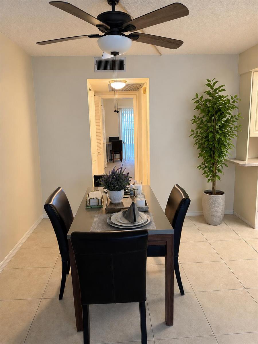 A dining area features a dark wood table with four black chairs and a ceiling fan — 3067 Yarmouth D, Boca Raton FL 33434, BOCA RATON, FL