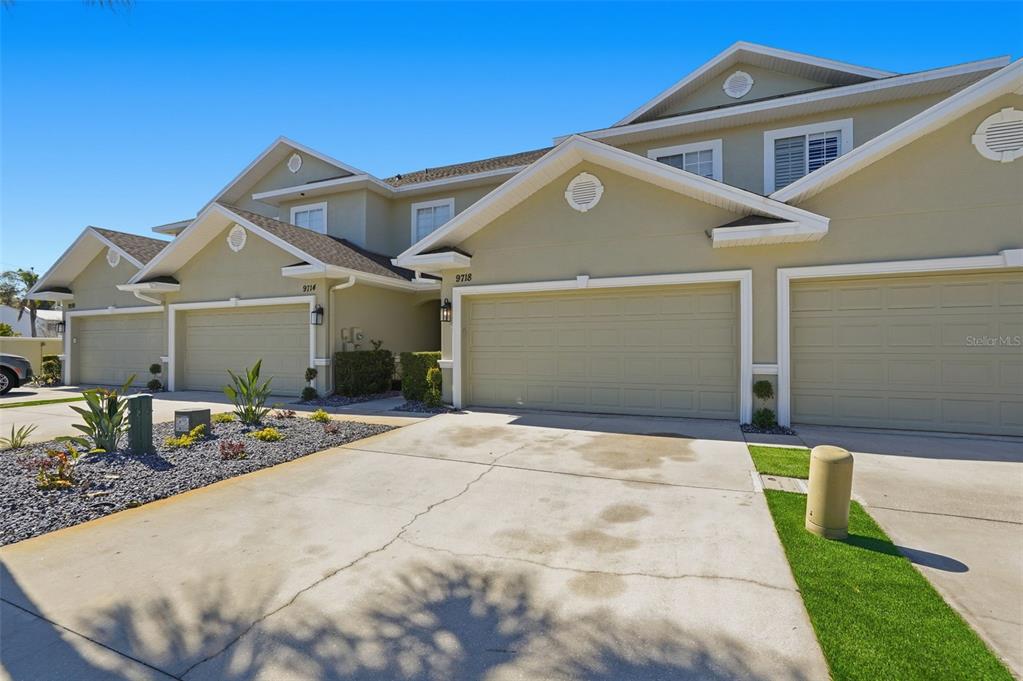 A row of multi-story townhomes features beige stucco siding, gabled roofs, and attached garages — 9718 TAYLOR ROSE LANE, SEMINOLE, FL