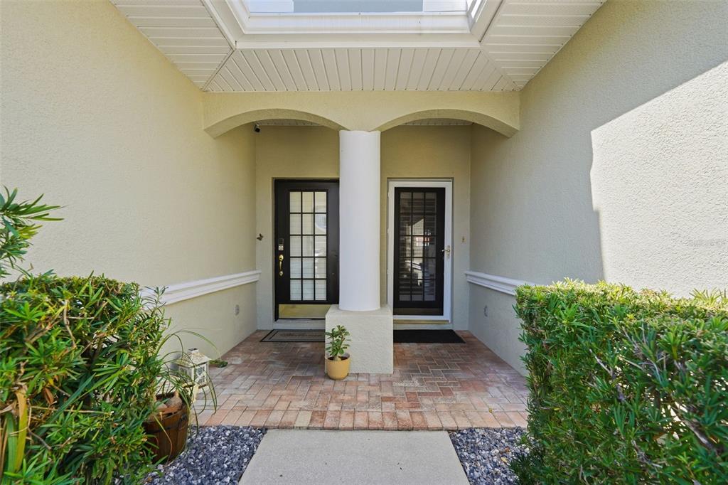 A covered entryway features two glass-paneled doors separated by a central white column — 9718 TAYLOR ROSE LANE, SEMINOLE, FL
