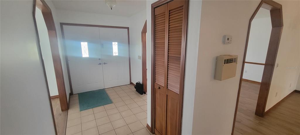 An entryway features tiled flooring, a double front door, and a wooden louvered closet door — 1991 TILBURG AVENUE, DELTONA, FL