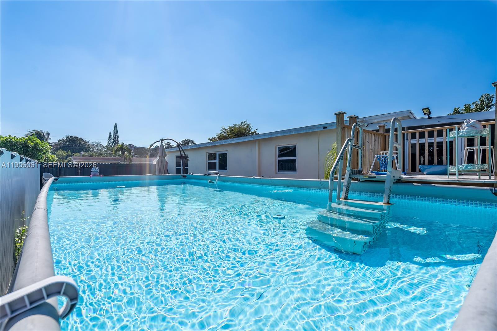 An above-ground swimming pool with a ladder sits in a backyard next to a house — 1031 NE 213th Ter, Miami FL 33179, MIAMI, FL