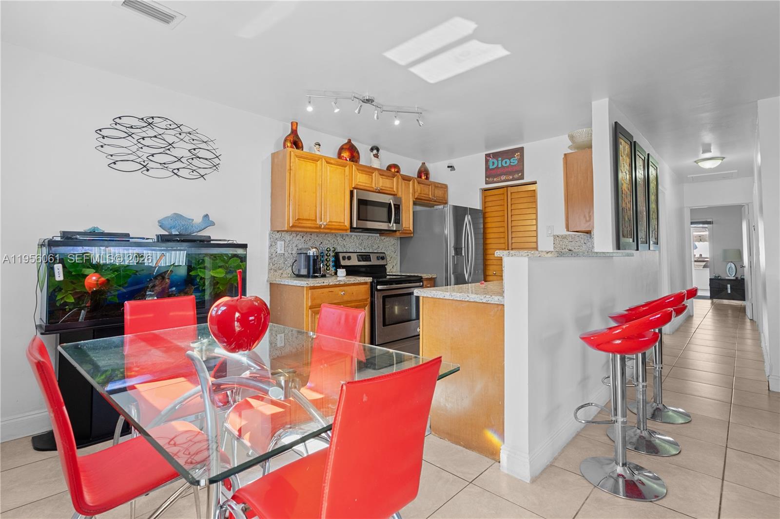 A kitchen and dining area features red chairs, a glass table, and a fish tank — 1031 NE 213th Ter, Miami FL 33179, MIAMI, FL