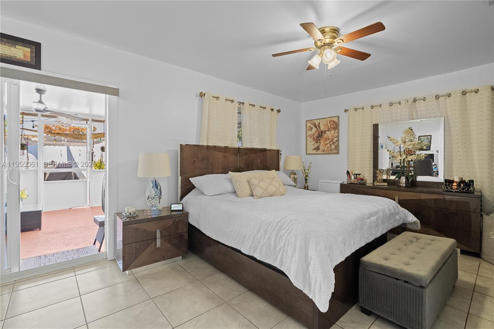 A bedroom features a bed, dresser, ceiling fan, and a sliding door to a patio — 1031 NE 213th Ter, Miami FL 33179, MIAMI, FL