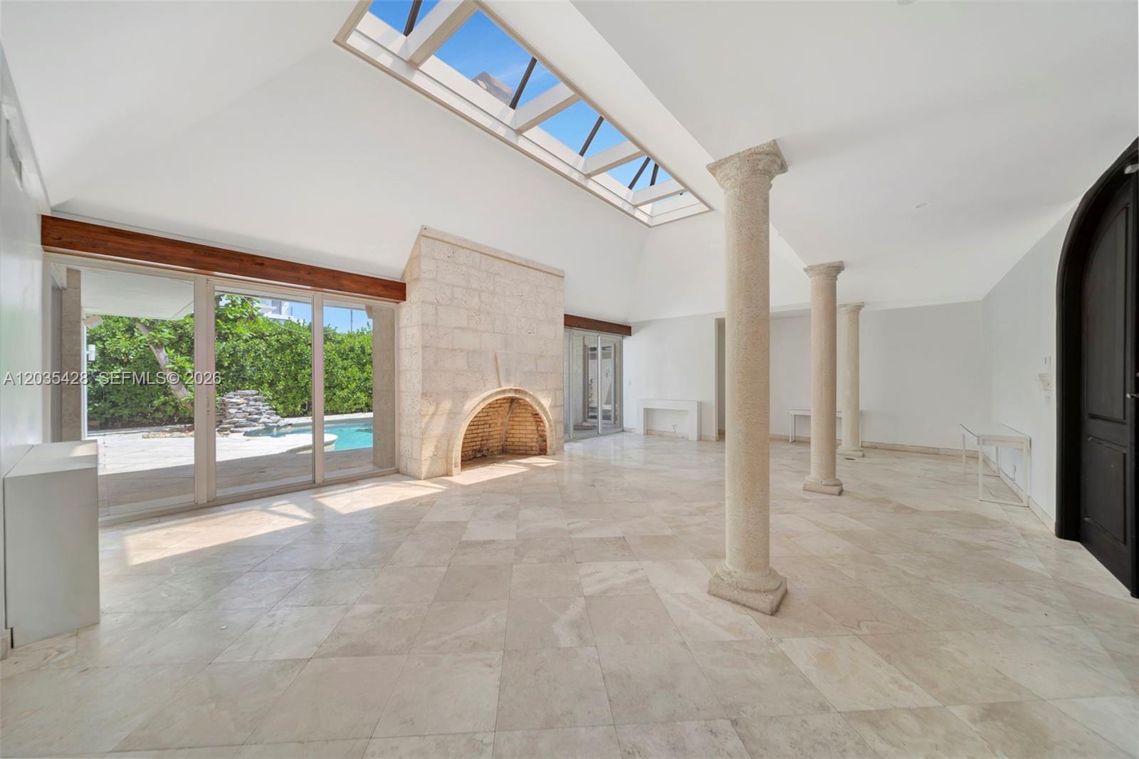 A bright living room features a stone fireplace, skylights, marble floors, and classical columns — 111 S Hibiscus Dr, Miami Beach FL 33139, MIAMI BEACH, FL