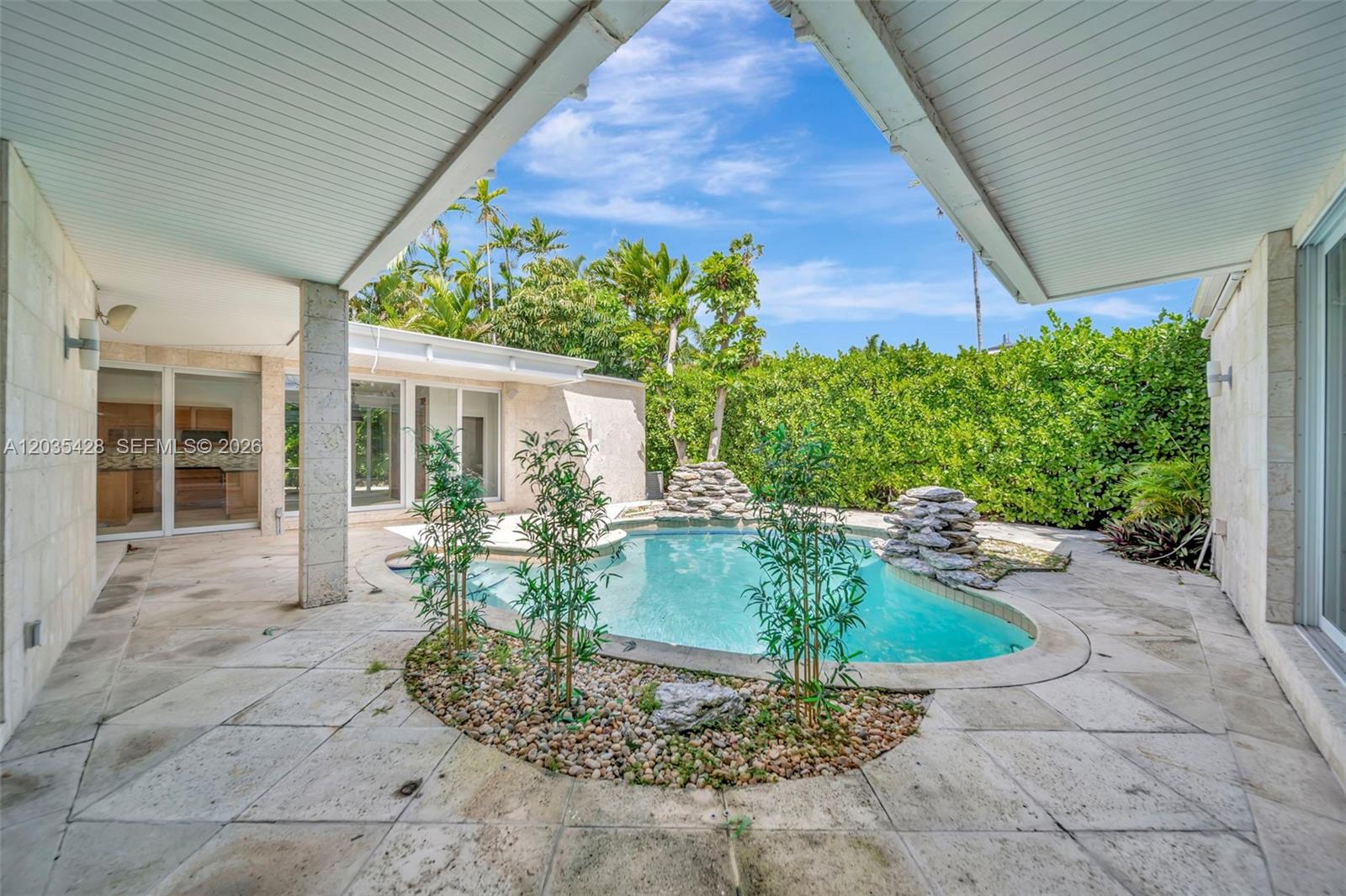 A patio features a kidney-shaped swimming pool with rock features and a small garden bed — 111 S Hibiscus Dr, Miami Beach FL 33139, MIAMI BEACH, FL