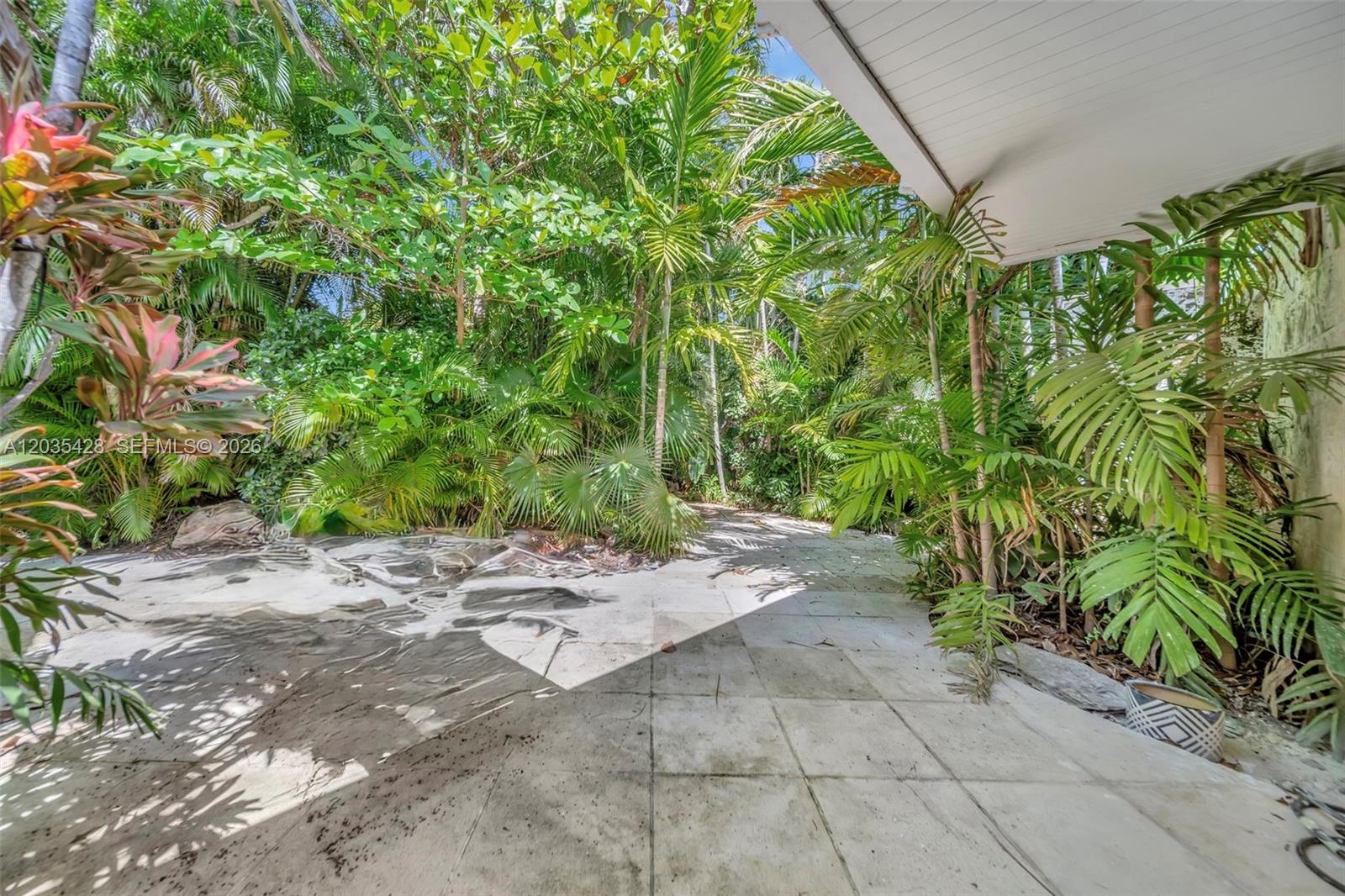 A paved patio area is surrounded by lush tropical foliage and palm trees — 111 S Hibiscus Dr, Miami Beach FL 33139, MIAMI BEACH, FL