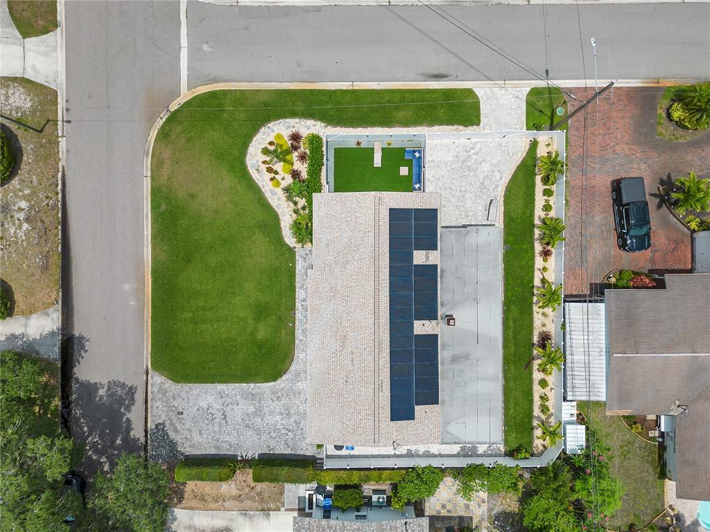 An aerial view shows a house with solar panels, a pool, and a landscaped yard — 3295 57TH STREET N, ST PETERSBURG, FL