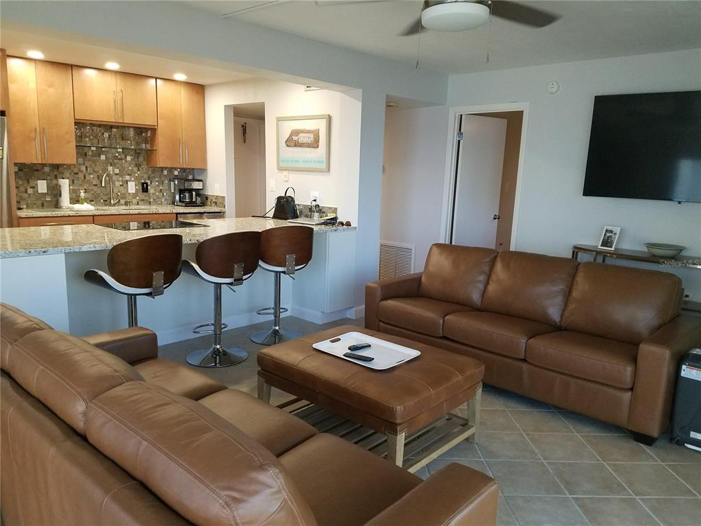 A living room with brown leather furniture opens to a kitchen with a breakfast bar — 1571 S ATLANTIC AVENUE UNIT 211, NEW SMYRNA BEACH, FL