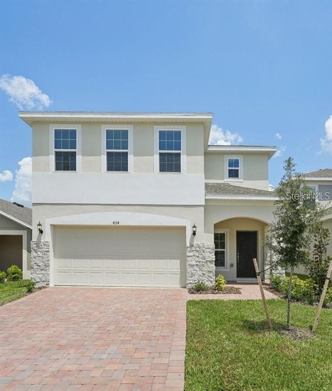 A two-story house features a beige stucco exterior, stone accents, and a paved driveway — 434 NORTH BOULEVARD E, DAVENPORT, FL