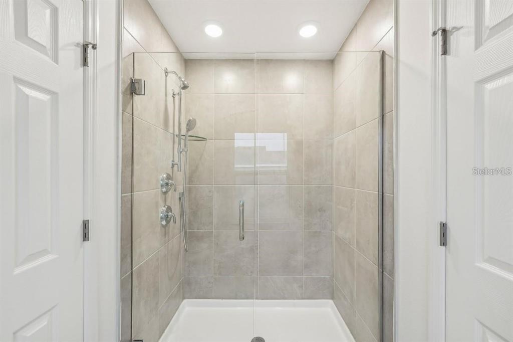 A walk-in shower with beige tiled walls, a glass door, and a white shower pan — 434 NORTH BOULEVARD E, DAVENPORT, FL