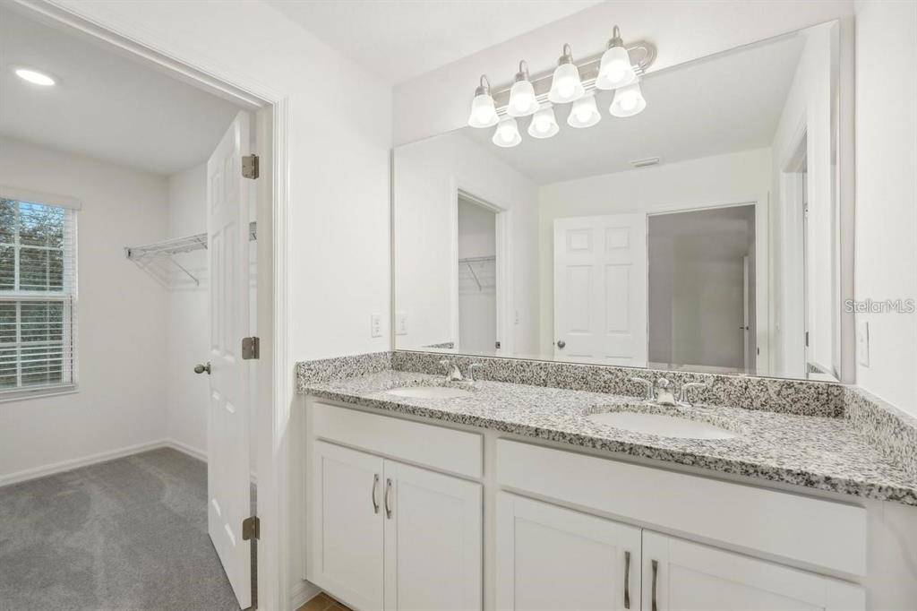 A bathroom with a double-sink granite vanity, white cabinets, and a large wall mirror — 434 NORTH BOULEVARD E, DAVENPORT, FL