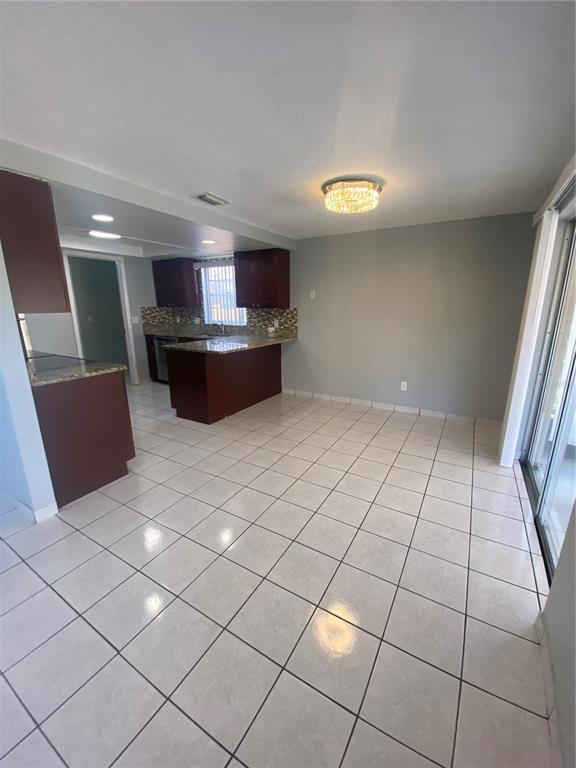 A kitchen with dark wood cabinets and a breakfast bar opens into a tiled dining area — 12703 ALIDA PLACE, TAMPA, FL