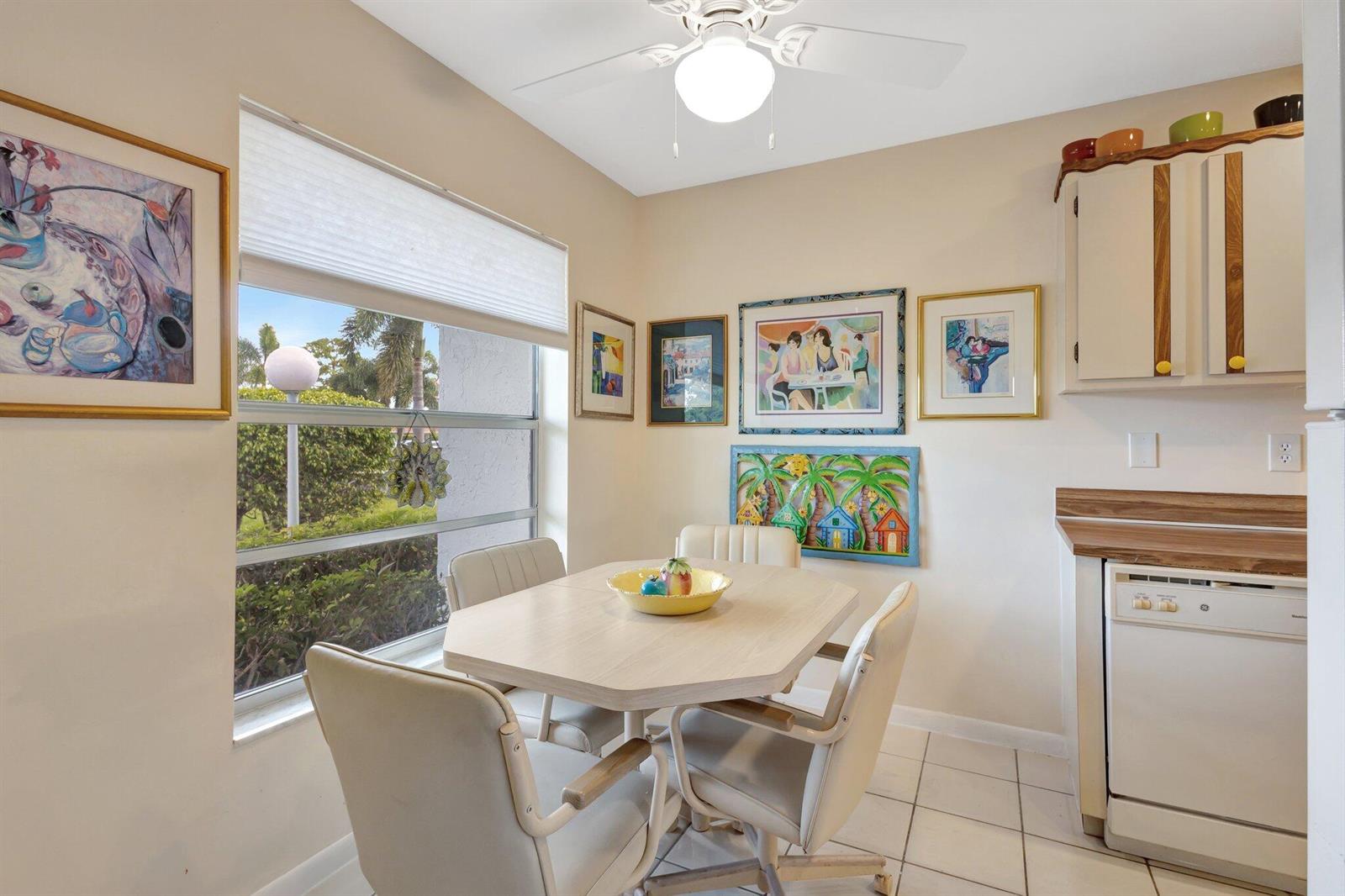 A dining area features a light-colored table, four chairs, tiled floors, and wall art — 5200 Privet B Place # B, Delray Beach FL 33484, DELRAY BEACH, FL