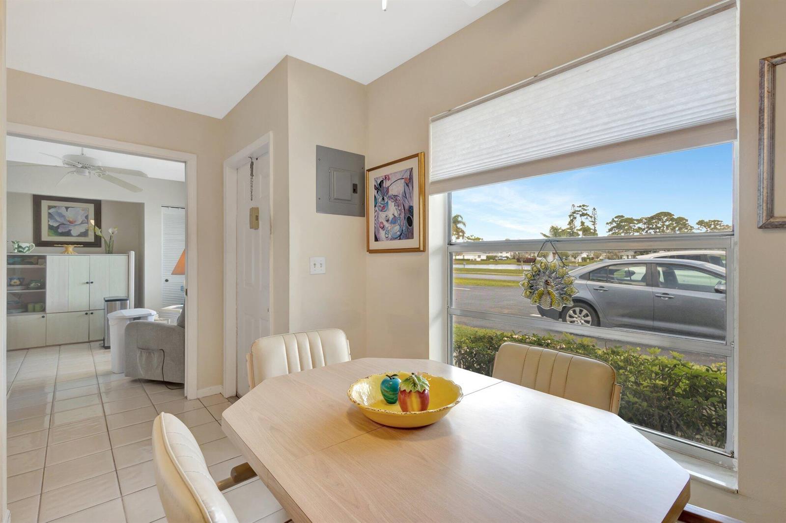 A dining area with a light wood table, chairs, and a window overlooking a parking lot — 5200 Privet B Place # B, Delray Beach FL 33484, DELRAY BEACH, FL