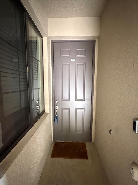 A brown front door with a small welcome mat is located in a recessed entryway — 18008 GAWTHROP DRIVE UNIT 302, BRADENTON, FL