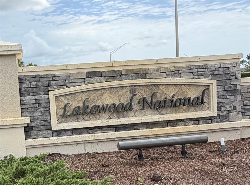 A stone monument sign for Lakewood National stands outdoors against a cloudy sky — 18008 GAWTHROP DRIVE UNIT 302, BRADENTON, FL
