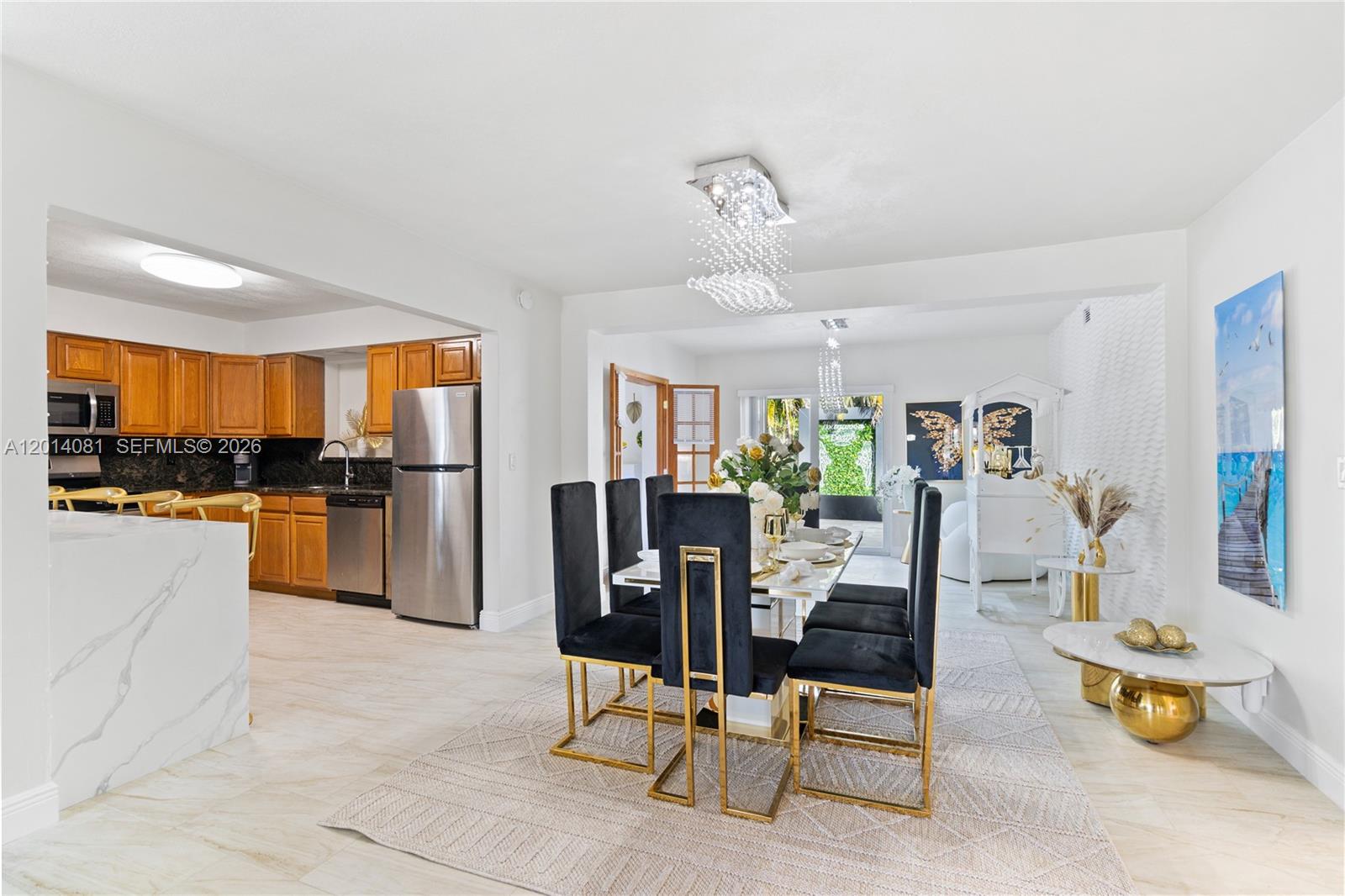 A dining area with a modern chandelier, black chairs, and an adjacent open-concept kitchen — 2125 N 14th Ct, Hollywood FL 33020, HOLLYWOOD, FL