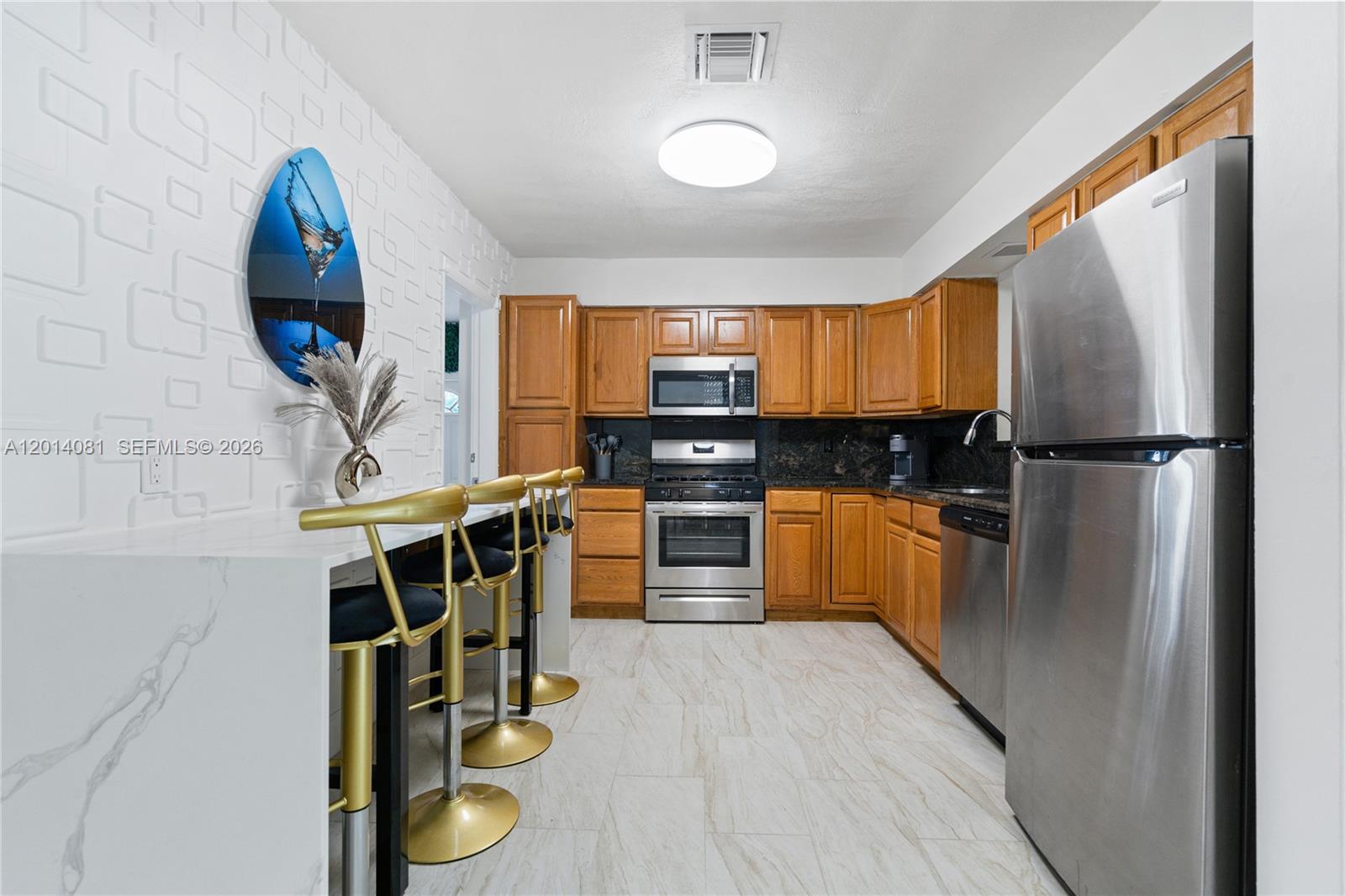 A kitchen features wood cabinets, stainless steel appliances, a white marble island, and bar stools — 2125 N 14th Ct, Hollywood FL 33020, HOLLYWOOD, FL