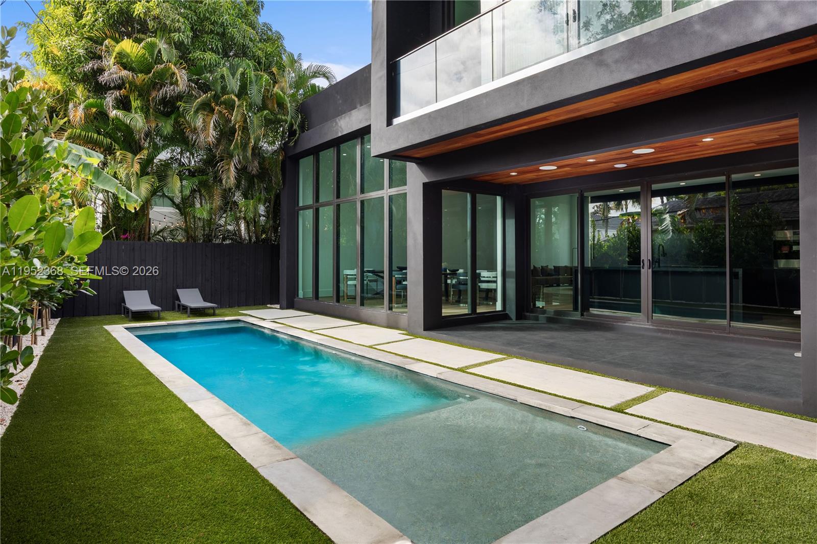 A modern house exterior features a rectangular swimming pool, artificial turf, and large glass windows — 30 NE 50th St, Miami FL 33137, MIAMI, FL