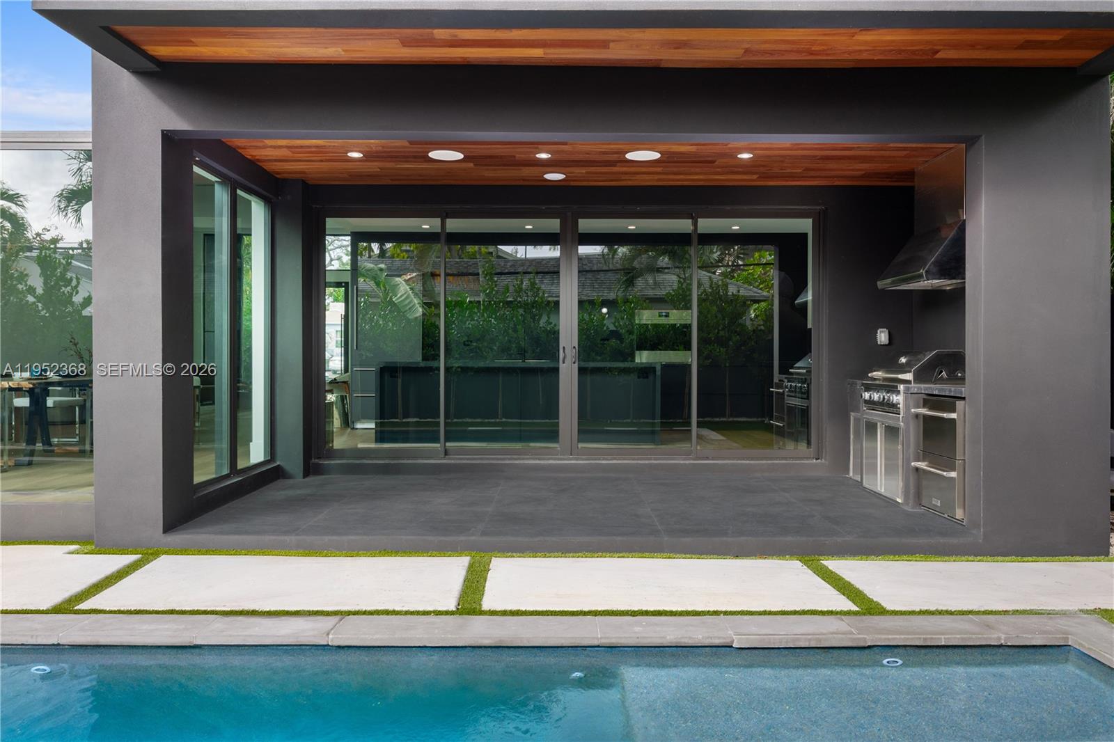 A covered patio features a built-in grill, dark tile flooring, and sliding glass doors — 30 NE 50th St, Miami FL 33137, MIAMI, FL