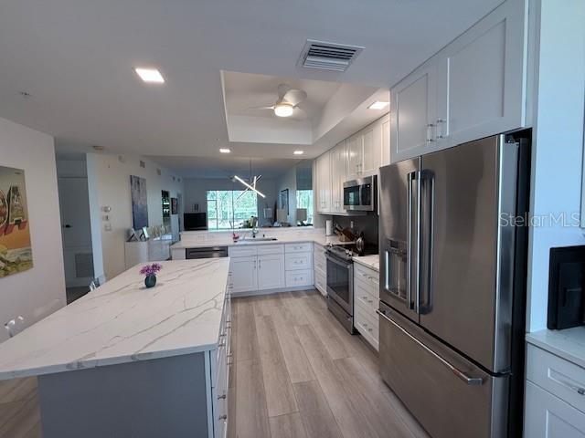 A modern kitchen features white cabinetry, a large marble-topped island, and stainless steel appliances — 8755 OLDE HICKORY AVENUE UNIT 7109, SARASOTA, FL