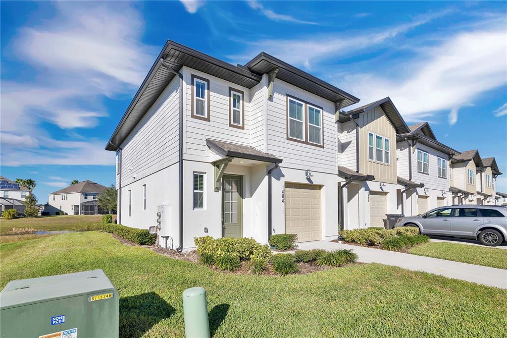 A two-story townhouse with white siding, a single-car garage, and a green front door — 1484 DISCOVERY STREET, DAVENPORT, FL