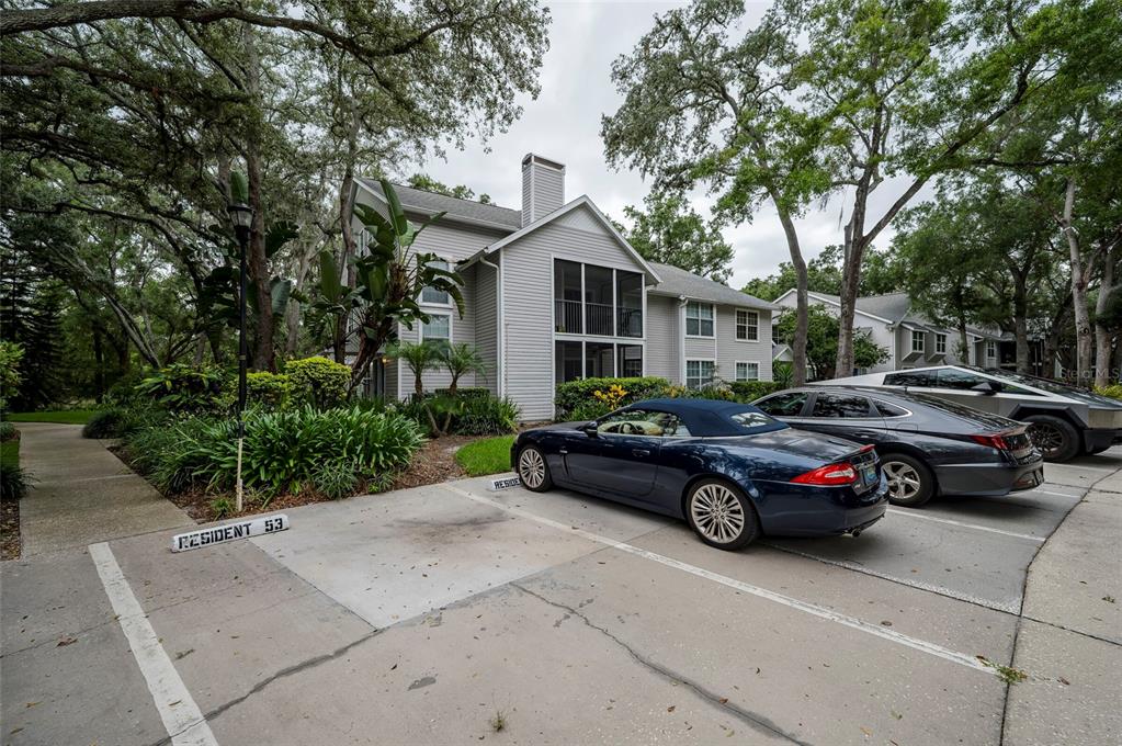 A multi-story apartment building with light siding stands behind a parking lot with several cars — 3164 VALLEY OAKS DRIVE UNIT 3164, TAMPA, FL