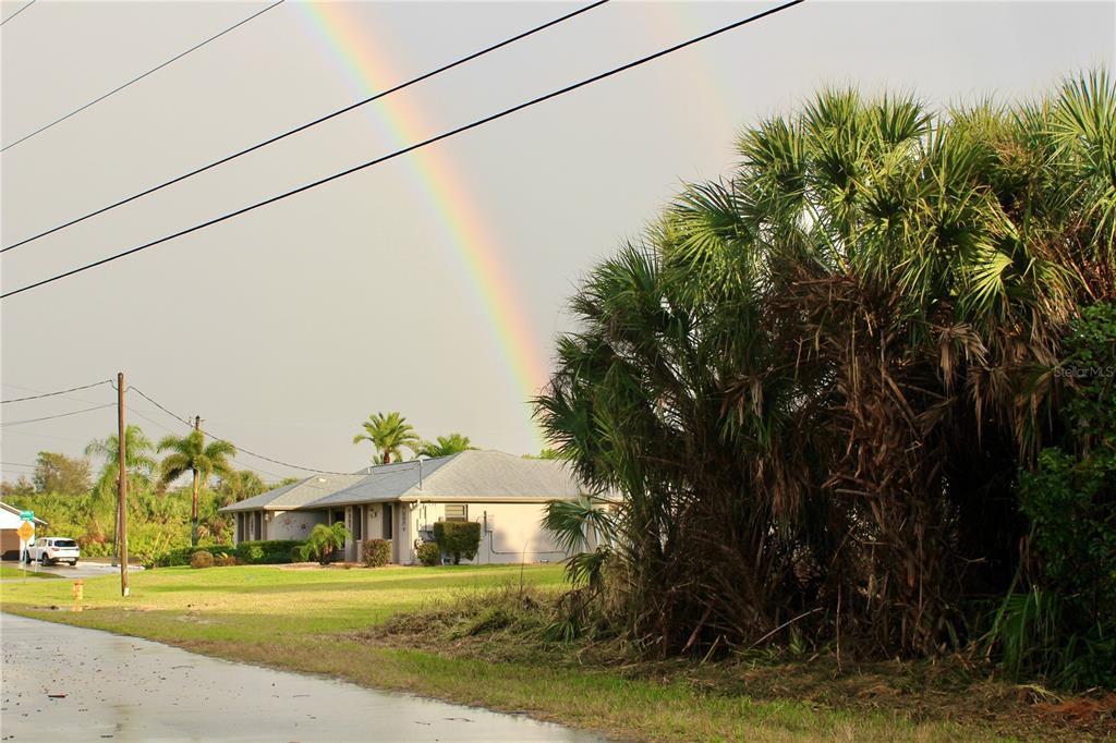A single-story house with a grey roof sits near palm trees under a double rainbow — 4402,4410 BAYVIEW STREET, PORT CHARLOTTE, FL