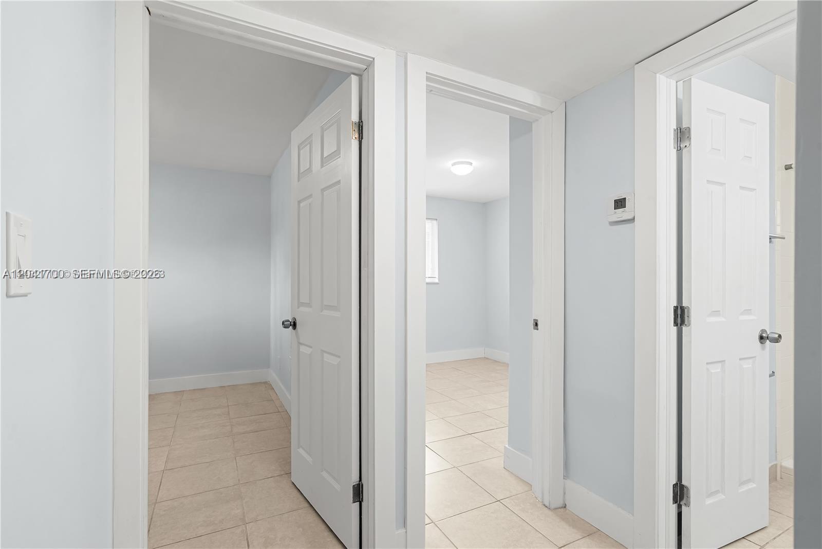 A hallway with light blue walls and tile flooring leads to two open doorways — 7722 NE 3rd Ct # 2, Miami FL 33138, MIAMI, FL