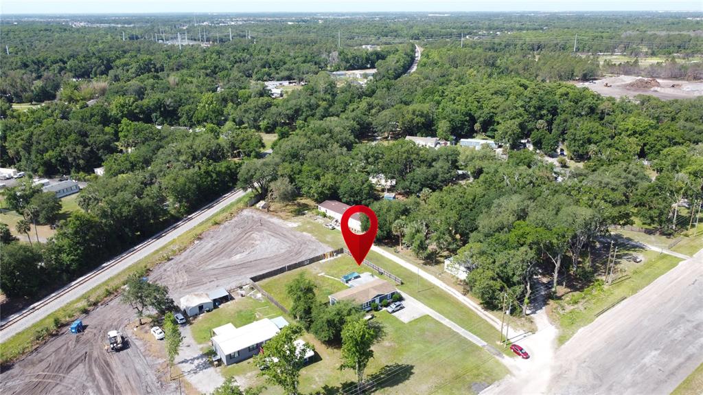 An aerial view shows a house with a red location pin in a wooded area — 6590 OSCEOLA POLK LINE ROAD, DAVENPORT, FL