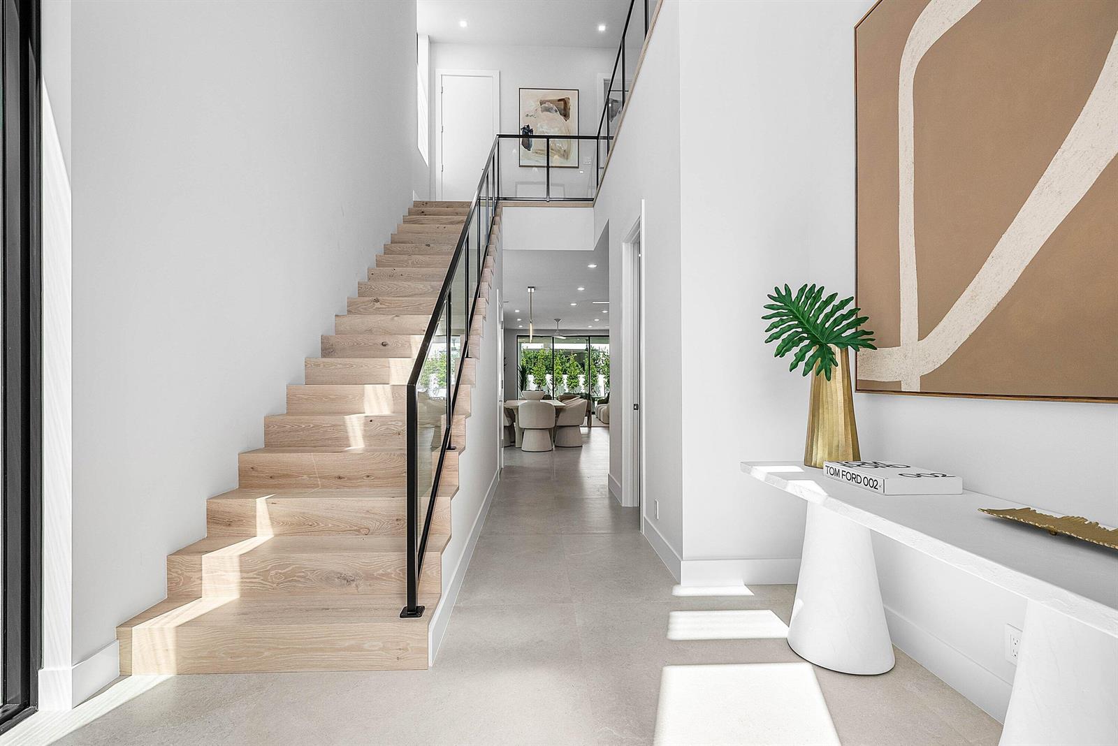 A modern entryway features a light wood staircase, a white console table, and tile flooring — 721 Lake Avenue N, Delray Beach FL 33483, DELRAY BEACH, FL