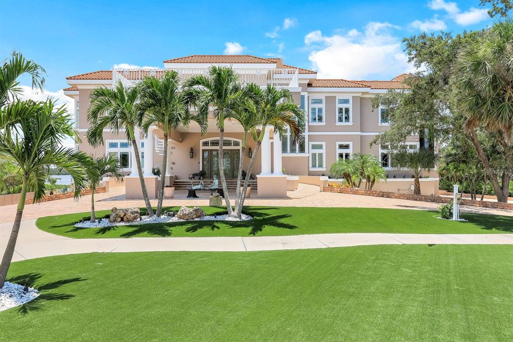 A large, two-story Mediterranean-style house with a tiled roof, palm trees, and a manicured lawn — 7159 MANASOTA KEY ROAD, ENGLEWOOD, FL