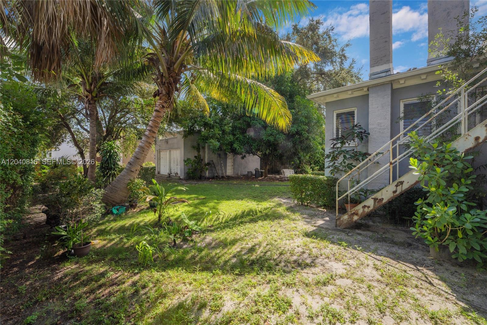 A backyard features a palm tree, a gray house with exterior stairs, and a detached garage — 405 SW 11th Ave, Miami FL 33130, MIAMI, FL