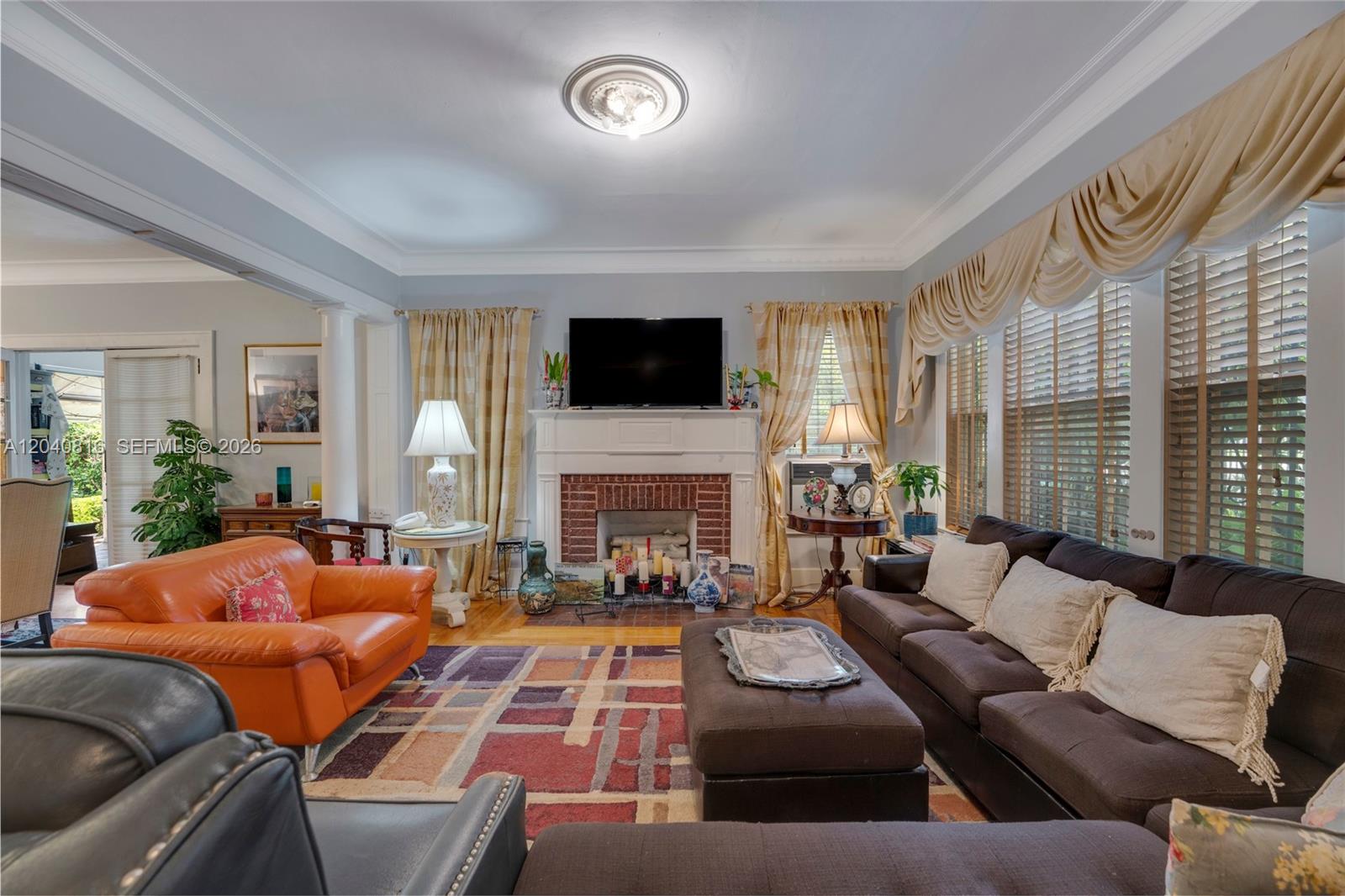 A living room features a brick fireplace, a television, and a colorful area rug — 405 SW 11th Ave, Miami FL 33130, MIAMI, FL
