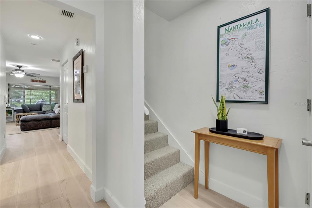 A hallway features a staircase with carpeted steps, a wooden console table, and wall art — 1637 SE PARADISE CIRCLE UNIT 106, CRYSTAL RIVER, FL