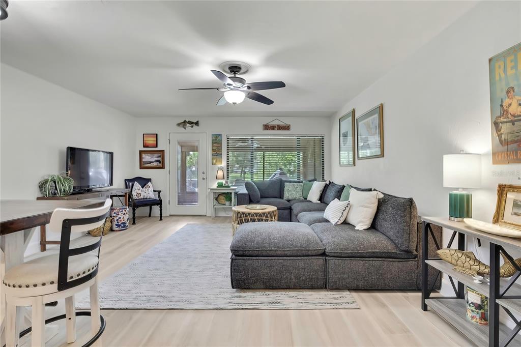 A living room features a gray sectional sofa, a ceiling fan, and light wood flooring — 1637 SE PARADISE CIRCLE UNIT 106, CRYSTAL RIVER, FL